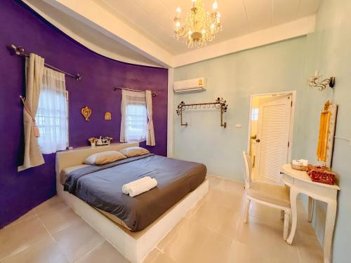 a bedroom with purple walls and a bed and a table at เนริสารีสอร์ท เขาค้อ in Ban Khao Ya Nua