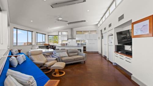 a living room with a blue couch and a kitchen at Walshys Shack in Coffin Bay