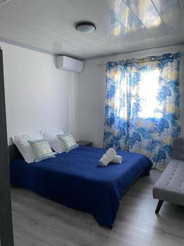 a bedroom with a blue bed and a window at La villa Cannelle maison 1 in Étang-Salé