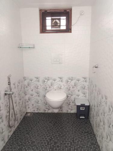 a bathroom with a toilet and a window at Kochi Bella Villa in Cochin