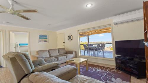 sala de estar con sofá y TV de pantalla plana en Mariners View Coffin Bay en Coffin Bay