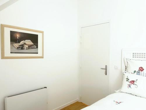 a white bedroom with a bed and a picture on the wall at Place Sainte Marguerite in Provins