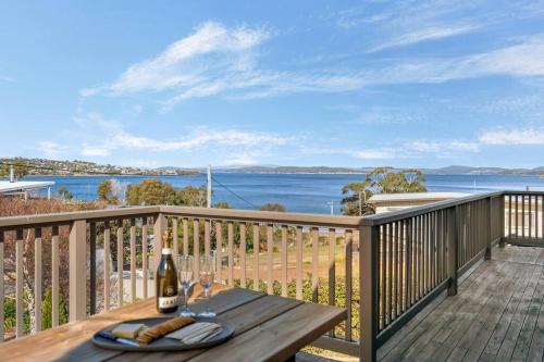 a wooden deck with a table with a bottle of wine at Escape to Coastal Tranquility in Primrose Sands