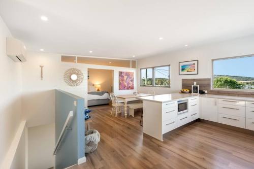 a kitchen and living room with white cabinets and a table at Escape to Coastal Tranquility in Primrose Sands