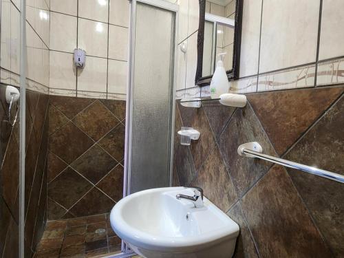 a bathroom with a sink and a shower and a mirror at Agros Guest House in Kimberley