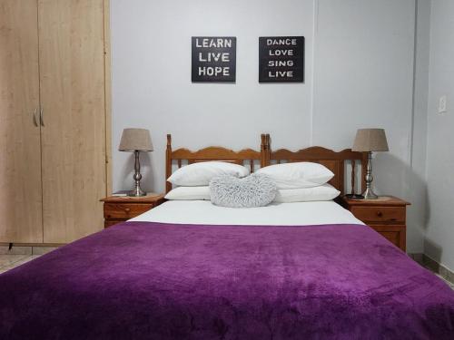a bed with a purple blanket on top of it at Agros Guest House in Kimberley