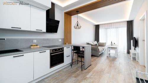 une cuisine avec des armoires blanches et un salon dans l'établissement Wonder Home - Apartamenty Karpatia Resort tuż przy stoku i blisko szlaków turystycznych, à Karpacz
