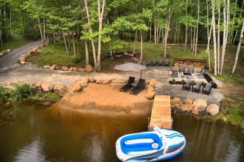 a boat sitting on the water next to a dock at KALLM-Mont-Tremblant chalet with hot tub, pond & beach on private 7acre estate in Lac-Superieur