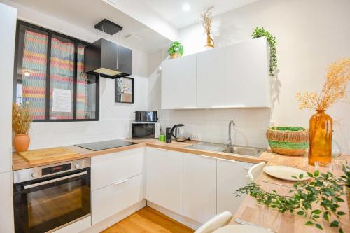 une cuisine avec des armoires blanches et une table en bois dans l'établissement Bel appart 2 ch clim à Vauban proche Vieux-Port, à Marseille