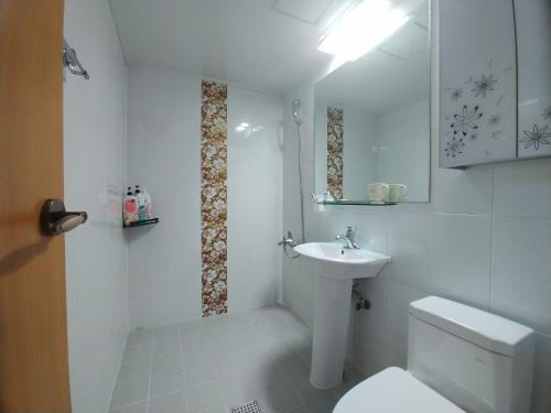 a white bathroom with a toilet and a sink at Beljari Pension in Tongyeong