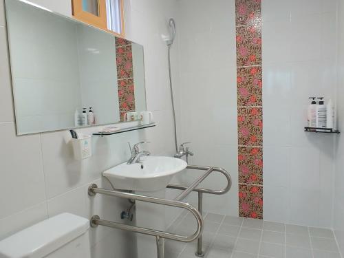 a white bathroom with a sink and a mirror at Beljari Pension in Tongyeong