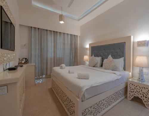 a white bedroom with a large bed and a desk at Lillywoods NV Beach Resort in Calangute
