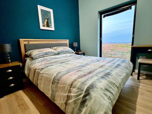 1 dormitorio con cama y ventana grande en The Bothy, Vatten, Dunvegan, en Lonmore