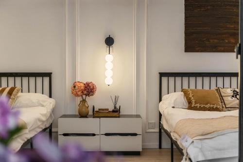 a bedroom with two beds and a table with flowers at Shanghai Yi Du B&B - Family Suite 500m to Nanjing West Rd Near People's Square -Credit Cards Accepted in Shanghai