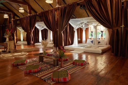 een woonkamer met een bed met gordijnen en een houten vloer bij The BanBa Jungle Lodge in Làng Hoa (2)