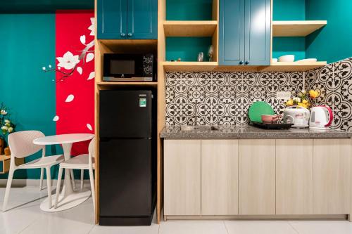 a kitchen with blue cabinets and a black refrigerator at Otis Soho Saigon Balcony Apartment in Ho Chi Minh City