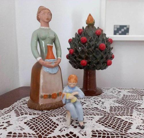 a figurine of a woman sitting on a table next to a statue at Lankás Vendégház - Hollókő in Hollókő