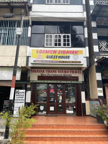 un negozio con un cartello di fronte a un edificio di Losmen Sibayak Berastagi a Berastagi