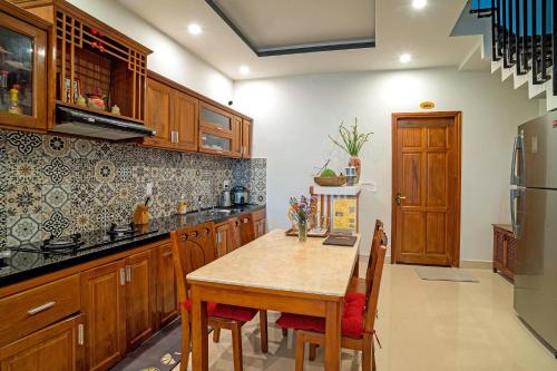 a kitchen with wooden cabinets and a table with chairs at Phuoc Dat Riverside Homestay Hoi An in Hoi An