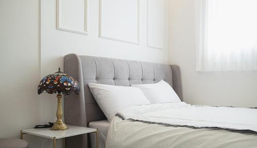 a bed with a lamp on a table next to it at Homechee Poolvilla in Jeju