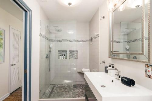 uma casa de banho branca com um lavatório e um chuveiro em Flamingo Bay Coastal Oasis: Modern Comforts, Heated Pool w/ BBQ em Tampa