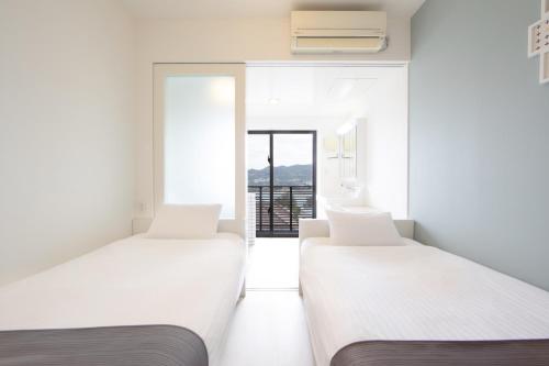 two beds in a room with a window at E-horizon Resort Condominium Sesoko in Motobu