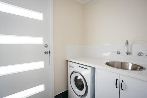 a white kitchen with a sink and a washing machine at Owen's Hideaway by the BnB Collection in Albany
