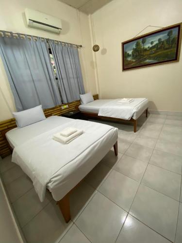 a hotel room with two beds and a window at Ecran Riverfront Guesthouse in Kampot
