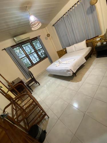a bedroom with a white bed and two windows at Ecran Riverfront Guesthouse in Kampot