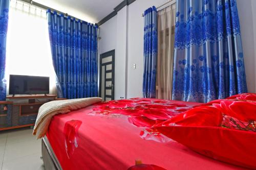 a bedroom with a red bed with blue curtains at Wisma Barokah in Tebingtinggi