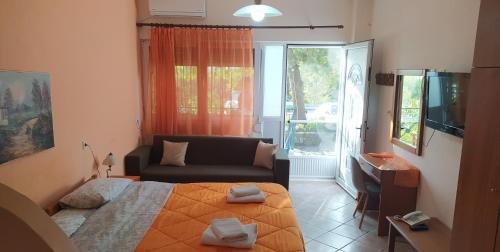 una camera da letto con un letto, un divano e una televisione di Drosia Hotel a Kato Loutraki