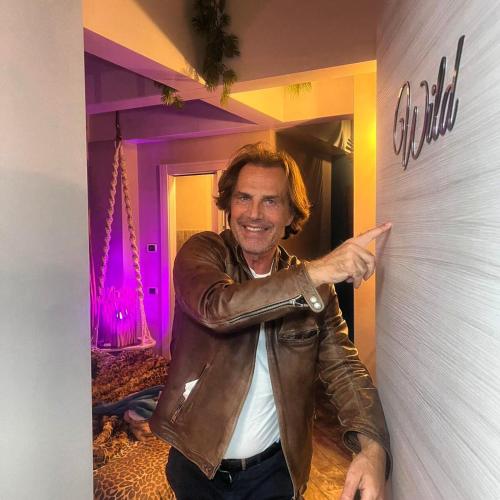 a man in a leather jacket standing next to a wall at B&B Bellavista Exclusive in zona centrale con piscina riscaldata e Jacuzzi vista lago LA COLAZIONE viene servita in una pasticceria rinomata ed esclusiva esterna alla struttura in Desenzano del Garda