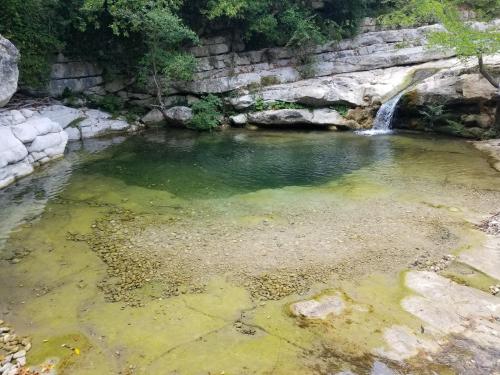 a pool of green water with a waterfall at La Cérisole in Saint-Étienne-de-Tinée