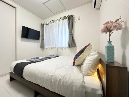 a bedroom with a bed with white sheets and a window at nestay villa tokyo sugamo in Tokyo