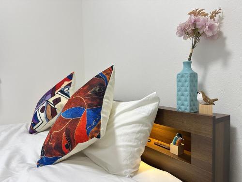 a bed with two pillows and a vase with flowers at nestay villa tokyo sugamo in Tokyo
