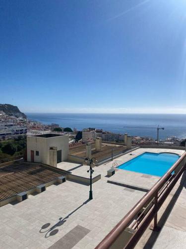 a swimming pool on top of a building with the ocean at Notre paradis à Sesimbra in Sesimbra