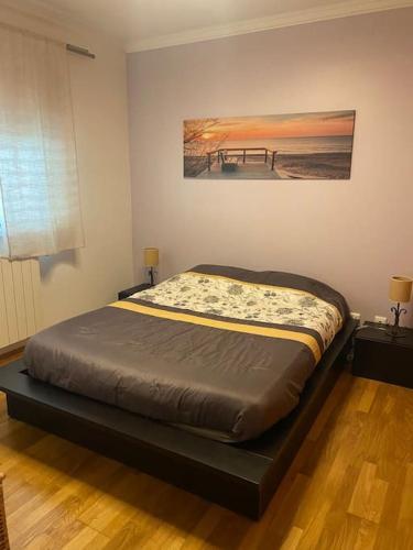 a bed in a bedroom with a painting on the wall at Notre paradis à Sesimbra in Sesimbra