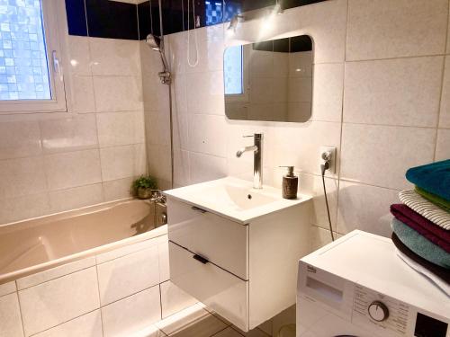 y baño blanco con lavabo y bañera. en Villa 110m2, 7 pers, Jacuzzi , 3 chambres, terrain clos et arboré 2500m2, en Trèbes