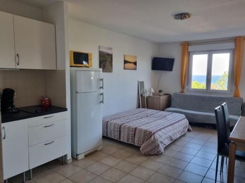 a bedroom with a bed and a kitchen with a window at Appartement dans la residence calme in Saint-Florent