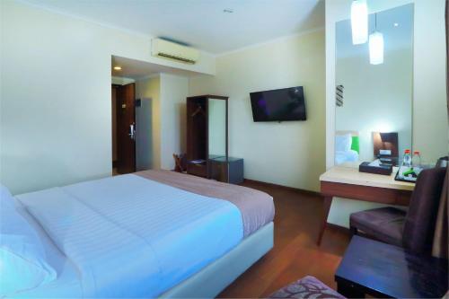 a hotel room with a white bed and a chair at Hotel Dafam Pekalongan in Pekalongan