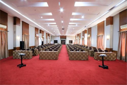 Habitación grande con sillas y alfombra roja. en Hotel Dafam Pekalongan en Pekalongan