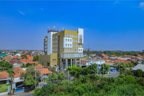 a tall yellow and white building in a city at Hotel Dafam Pekalongan in Pekalongan