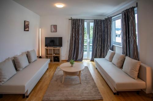 a living room with two white couches and a table at NEW East Side Apartment Innsbruck I Free Parking in Innsbruck