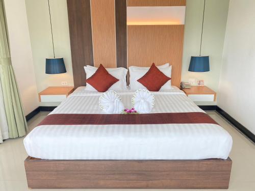 a bedroom with a large white bed with red pillows at Siva Royal Hotel in Phatthalung