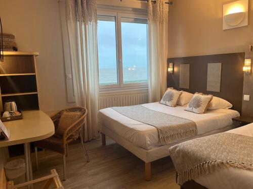 1 dormitorio con 2 camas, escritorio y ventana en Acadie Saint Victor - Hôtel restaurant - Face mer - Chatelaillon plage, en Châtelaillon-Plage