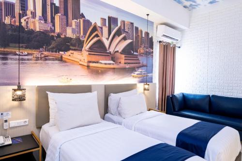 a hotel room with two beds and a picture of the sydney opera house at Premiere Hotel Tegal in Tegal
