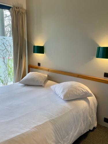 a bedroom with a bed with two pillows and two lamps at Logis Hôtel Le Keréden in Locarn
