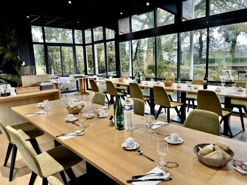 - un restaurant avec de longues tables, des chaises et des fenêtres dans l'établissement Le Keréden - Breizh Ecolodge Hôtel, à Locarn