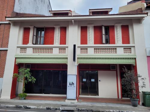 a white building with red shutters on it at Wink at Perak Road in Singapore