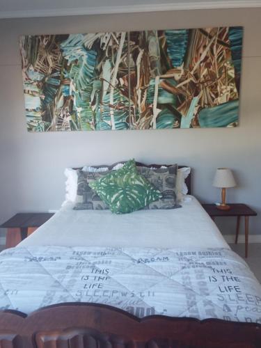 1 dormitorio con 1 cama con una pintura en la pared en Modern Comfy 2-Bedroom Self-catering Apartment - 1 minute walk to Strand beach en Strand